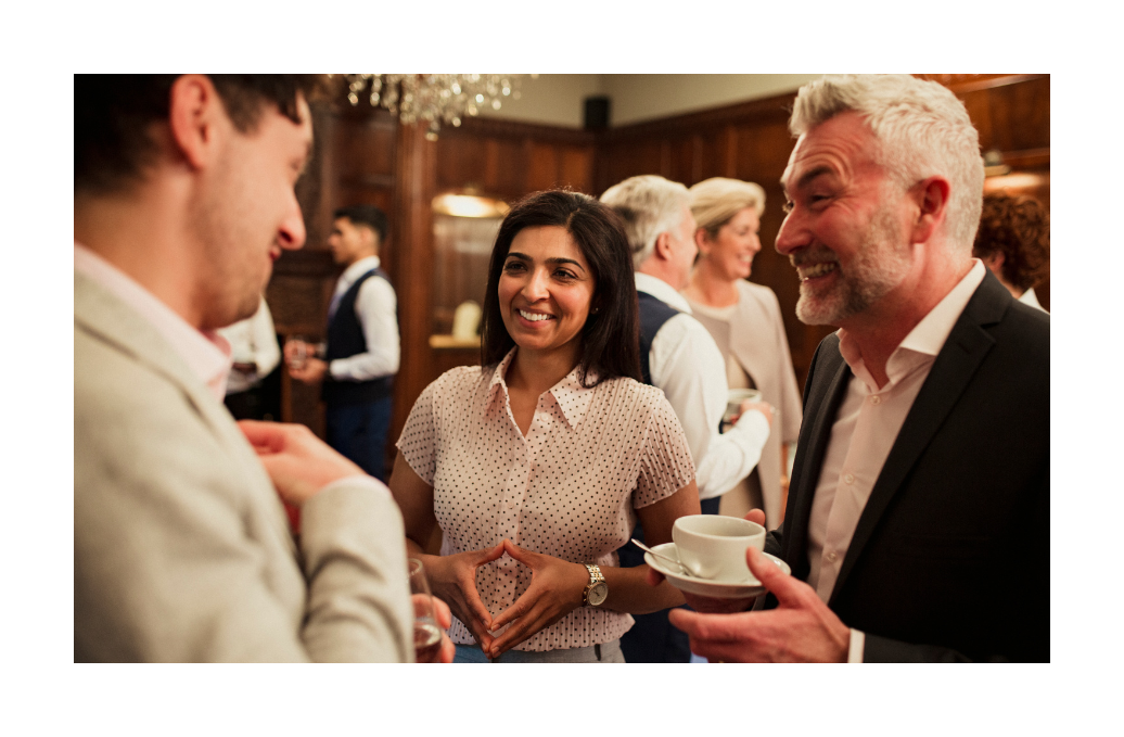 A woman smiling and engaging in conversation with two other attendees at a formal networking event.