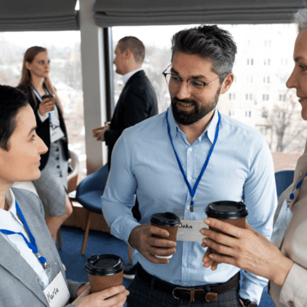 A small group of professionals with name tags having a casual conversation over coffee during a networking event.