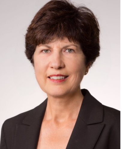 Portrait of Helen Tickle, a woman with short dark hair, wearing a dark blazer, smiling at the camera. The background is plain white, highlighting a professional appearance.