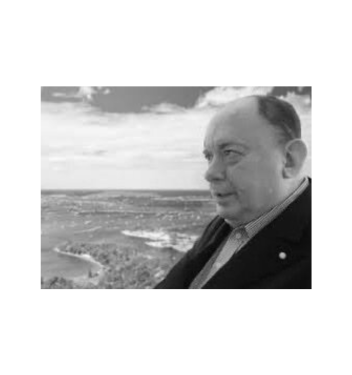 A black and white photo of William 'Bill' Galvin OAM, a distinguished leader in Australia's travel, tourism, and hospitality industry, with a serene landscape in the background. Bill is wearing a suit jacket and looking thoughtfully into the distance.